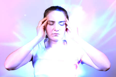 A woman holds her hands by the temple, concentrating during meditation. Disclosure of chakras in yoga, quantum theory of man, consciousness and physics.の写真素材