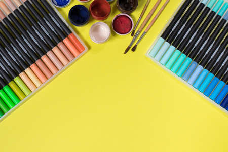Felt pens and paints for drawing on a yellow background with place for text. Stationery store.