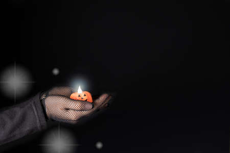 Beautiful Halloween banner on a black background copy space for text. A woman holds a glowing candle flashlight pumpkinの写真素材