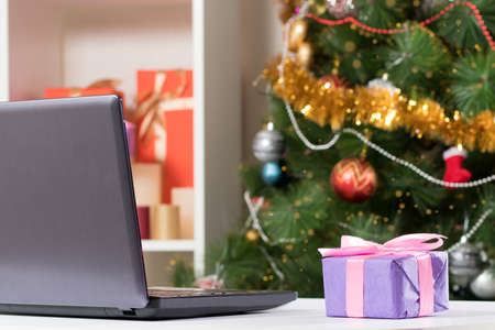Laptop near the Christmas tree. Buying gifts and congratulations online via the Internet.の写真素材