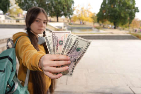 A teenage girl shows a lot of dollar bills with a place for text.の写真素材