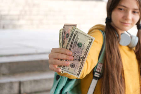 A teenage girl shows a lot of dollar bills and smiles with a place for text.の写真素材
