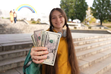 A teenage girl shows a lot of dollar bills and smiles.の写真素材