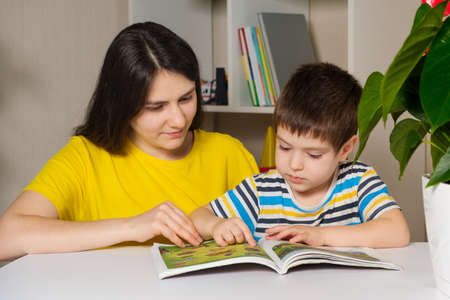 Mother and son read the book, look at the pictures on the pages. Leisure for children, spending time...