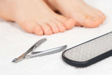 Womens feet and pedicure tools - nail polishing file and cuticle cutters on white backgroundの写真素材