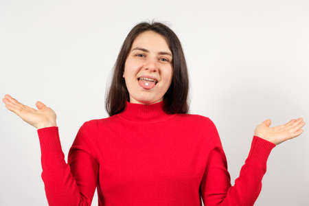 A woman with pills on her tongue spreads her arms apart on a white background.の写真素材