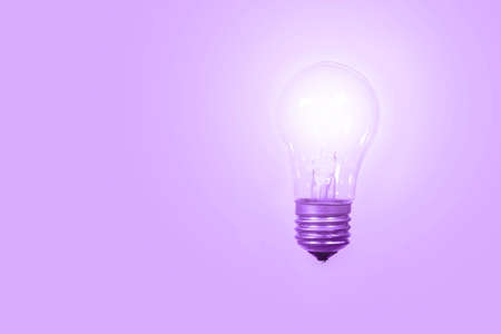 Glowing light bulb on a purple background, color very peri trendy 2022.の写真素材