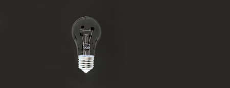 Light bulb on a black background, banner with space for text.