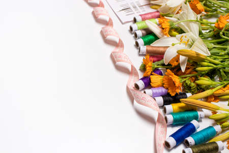 A set of threads and tape measure with flowers on a white background with place for text. Congratulations on the holiday to a seamstress, a tailor, an atelier worker. Happy tailors day, 8 March, birthdayの写真素材