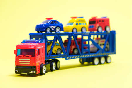 Toy car transporter with cars on a yellow background with place for text, copy space, for a toy store.の写真素材