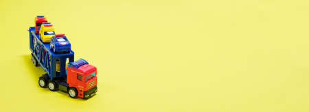 Toy car transporter with cars on a yellow background with place for text, copy space, for a toy...