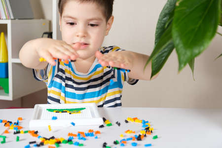 Preschooler child plays with mosaics, small objects for toddlers, careful use under adult supervision.の写真素材