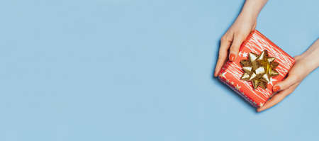 Beautiful red gift box with bow in womens hands, top view, copy space for text.の写真素材