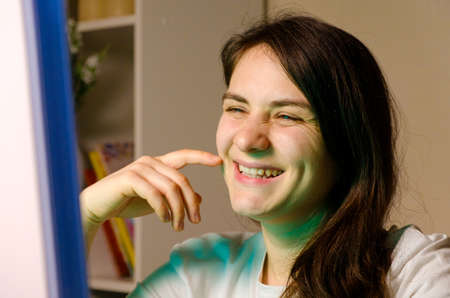 The woman looks at the computer screen and smiles.
