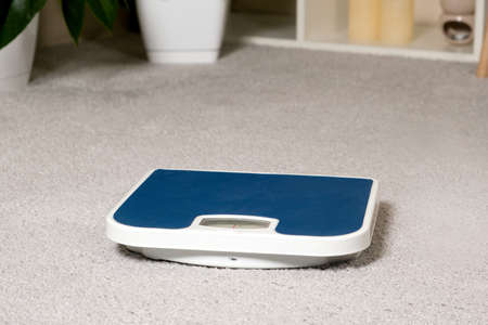Blue floor scales on the gray carpet in the room. The idea of losing weight and controlling a...