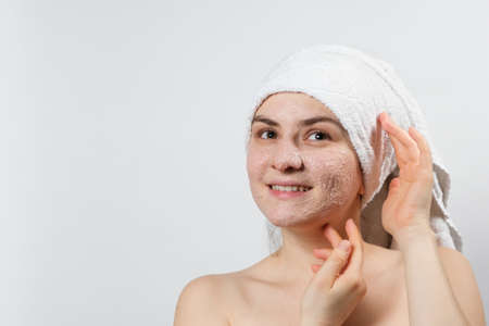 A young smiling woman with a natural mask or ubtan on her face and a white towel on her head, a place to text, copy spaceの写真素材