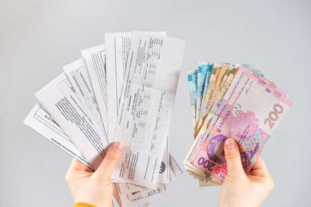Hryvnia banknotes and payments for utilities are in the hands of a person. Payment for gas, electricity and water in Ukraine.の写真素材
