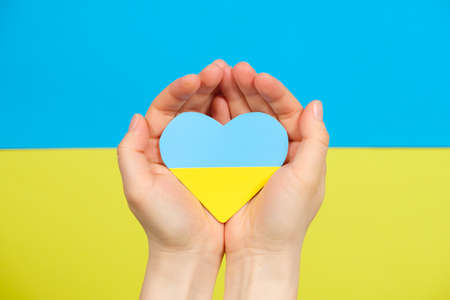 Yellow-blue heart in the color of the flag of Ukraine in the hands of a person, a place for text. Love for ones country, Constitution Day and Independence Dayの写真素材