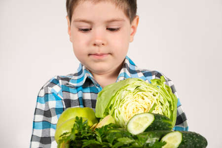 Preschool child and green vegetables - cabbage, cucumbers and parsley. Vitamins for childrenの写真素材