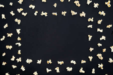 Popcorn scattered in the form of a frame on a black background, top view, space for text.の写真素材