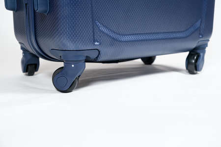 Rubber black wheels plastic blue suitcase on white background, copy space for text.の写真素材