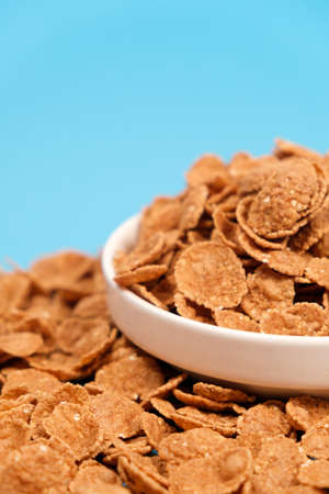 Durum wheat flakes - quick breakfast cereal on a plate on a blue background, space for text