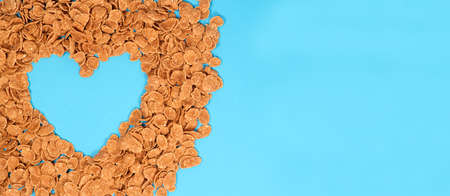 Cereals - heart-shaped breakfast with space for text on a blue background, top view.