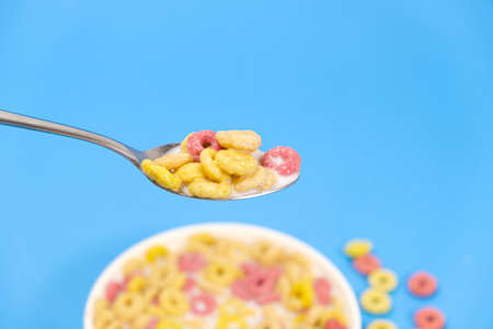 Cereal rings with milk, close-up in spoon, blue background with place for text.の写真素材