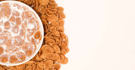 Cereal flakes drenched in milk in a plate, close-up view from above. Healthy delicious dairy...