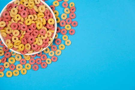 Corn rings of quick breakfast powder on a plate on a blue background, top view, place fot text.の写真素材