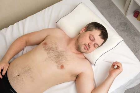 A young man lies on an orthopedic pillow on his back, view from above