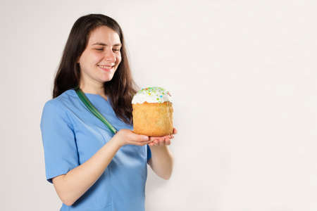 The doctor holds an Easter cake and smiles, a place for text. Medical Easter