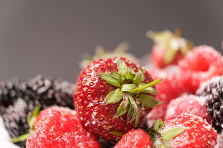 Raspberries, strawberries and blackberries sprinkled with sugar, close-upの写真素材