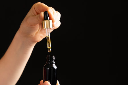 Natural oil for the care of eyelashes, eyebrows, facial skin drips into a glass jar of pipette