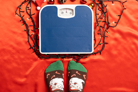 A woman is going to stand on the scales on a red background, weight after the Christmas holidaysの写真素材