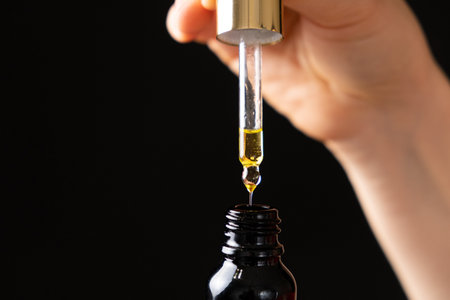 Natural oil for the care of eyelashes, eyebrows, facial skin drips into a glass jar of pipette.の写真素材