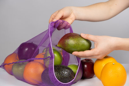 A woman puts fruit in a net. The concept of abandoning plastic shopping bags.の写真素材