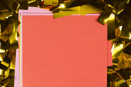 Red square sheet of paper on yellow sparkles, space for text, top view.の写真素材