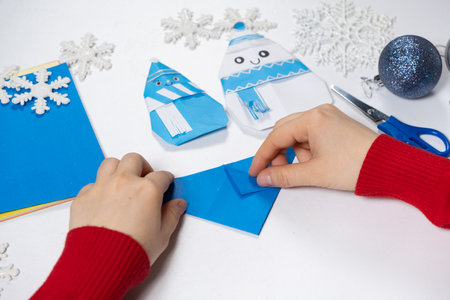 Creation of origami crafts from paper for Christmas and New Year, figurine of snowmen.