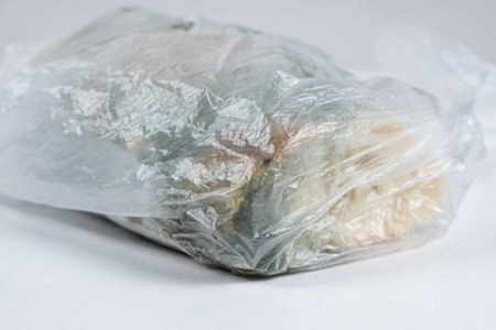 Bread with mold in a plastic bag on a white background, close-up.の写真素材