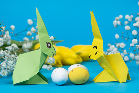 Two paper origami bunnies and an Easter eggs on a blue background. Crafts with your own hands for Easterの写真素材
