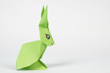 A green origami rabbit on a white background. Crafts for Easter, fold from paper, do it yourself, place for text.の写真素材