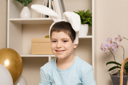 A 5 old preschool boy with rabbit ears on his head smiles. Easter and childrenの写真素材