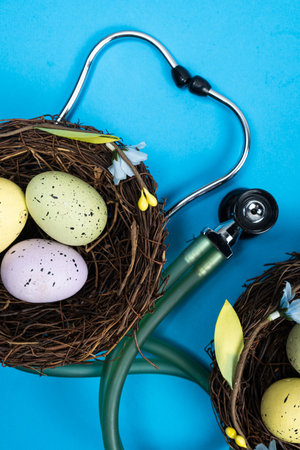 Easter Medicine. Two nests with painted eggs and a stethoscope on a blue backgroundの写真素材