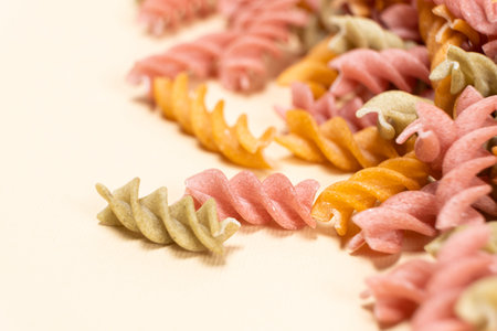 Rice vegetable pasta in the form of spirals on a white background. Healthy rice pasta with tomatoes, selenera, carrots and beets.の写真素材