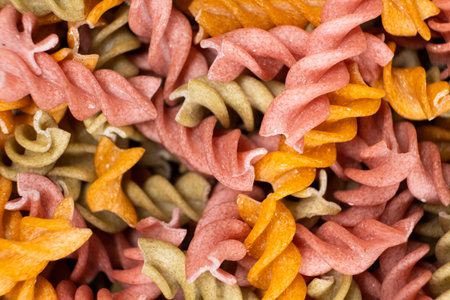 Rice vegetable pasta in the form of spirals, top view. Healthy rice pasta with tomatoes, selenera, carrots and beets.の写真素材