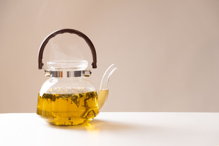 Green Chinese tea with orange zest in a glass teapot on a beige background.の写真素材