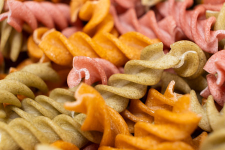 Rice vegetable pasta in the form of spirals, top view. Healthy rice pasta with tomatoes, celery, carrots and beets.の写真素材