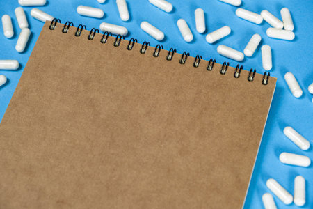 Medical notepad with pills on a blue background, space for textの写真素材