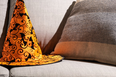 Orange Halloween hat on a gray sofa with a pillow. Textiles and Halloween, a place for textの写真素材